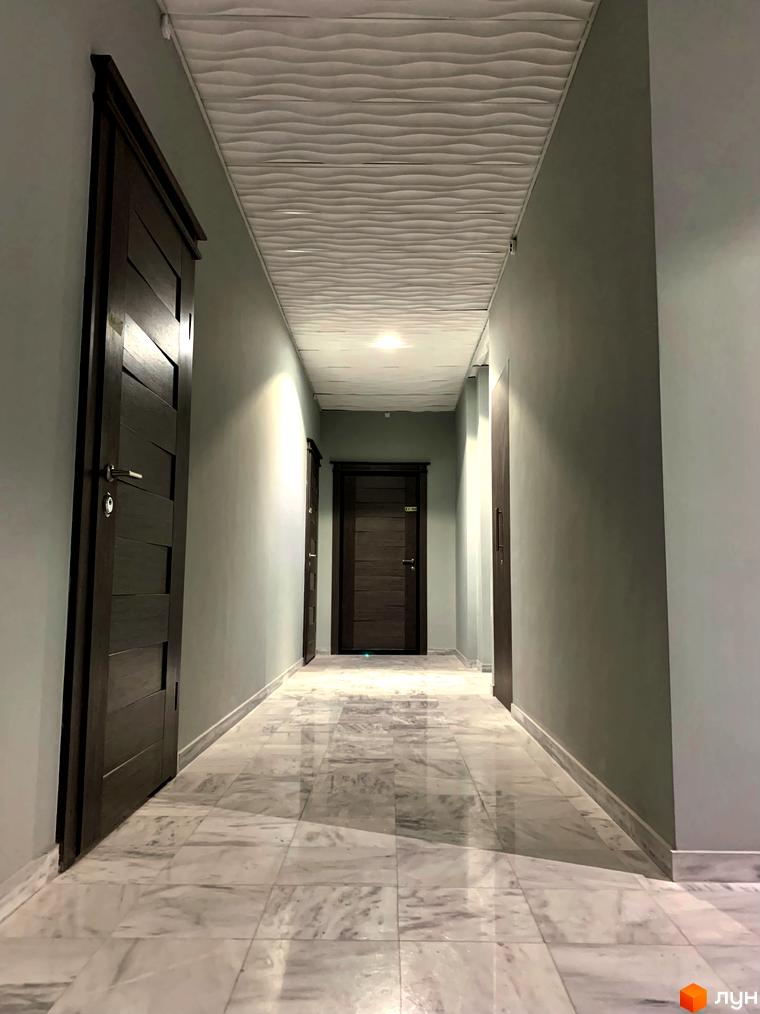 Інтер'єр коридору в Житловому комплексі Корфу з темними дверима та мармуровою підлогою. Вигляд внутрішнього простору з освітленням.
