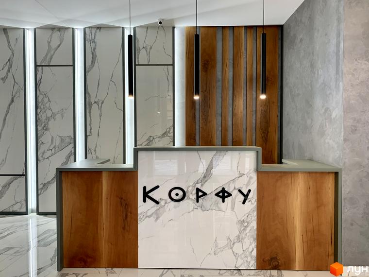 Сучасна рецепція житлового комплексу Корфу з мармуровим оздобленням та дерев'яними елементами. Стильний дизайн інтер'єру лобі новобудови.