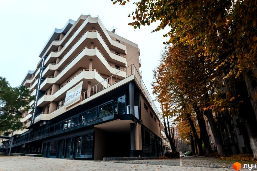 Житловий комплекс DREAM CITY з балконами хвилястої форми та комерційними приміщеннями на першому поверсі. Поруч ростуть дерева з осіннім листям.