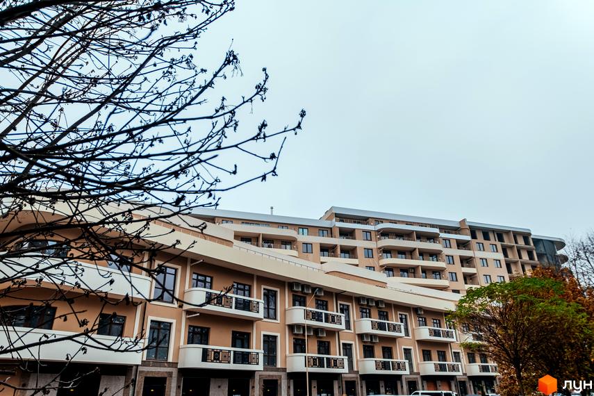 Житловий комплекс DREAM CITY з елегантною фасадною обробкою та балконами. Навколо будівлі видно дерева та частина прибудинкової території.