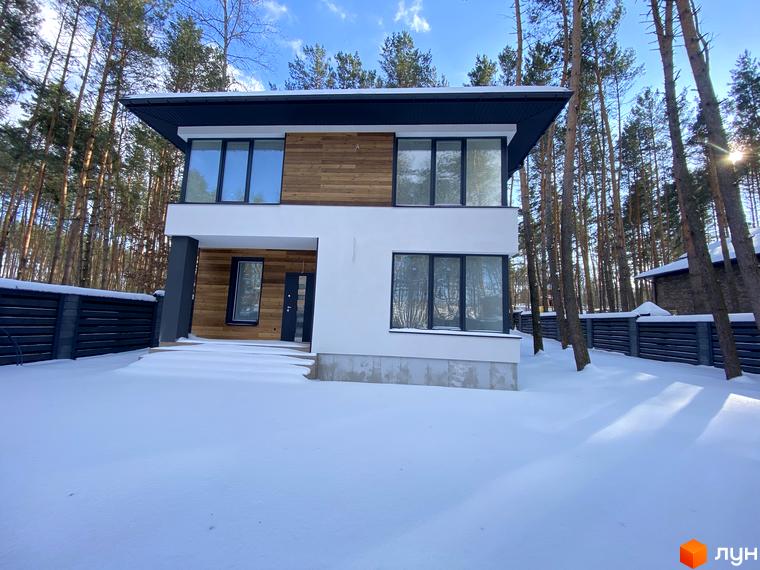 Двоповерховий будинок з великими вікнами та дерев'яним оздобленням фасаду в Котеджному містечку Квітка Полонини, вкритий снігом.