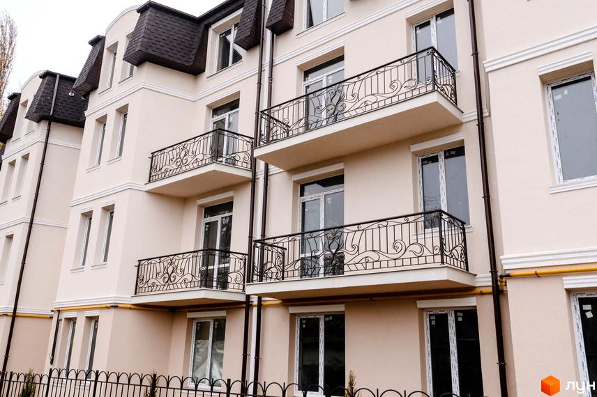 Фасад багатоповерхового будинку з балконами та кованими огорожами. На передньому плані — кована огорожа. Житловий комплекс на вулиці Академіка Вернадського (Тульська), 21а.