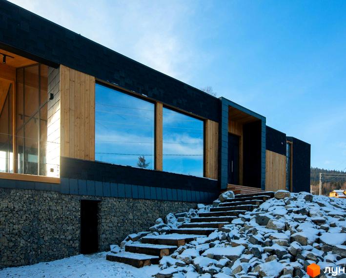 Фасад будинку КМ INO club з великими вікнами та дерев'яним оздобленням. Біля будинку сходи та кам'яниста територія, вкрита снігом.
