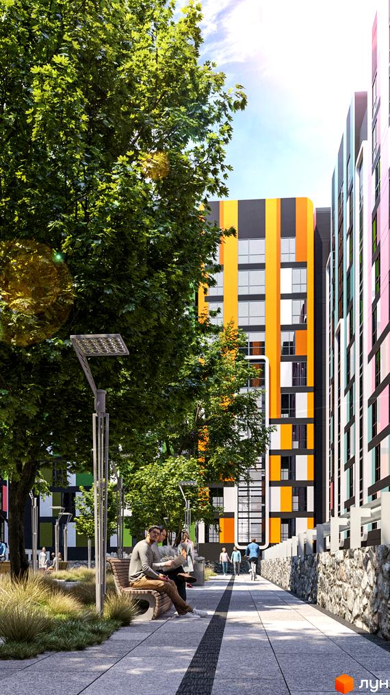 Житловий комплекс Карат: багатоповерхові будинки з яскравими вертикальними смугами на фасадах, зелені дерева та пішохідна алея з лавками.