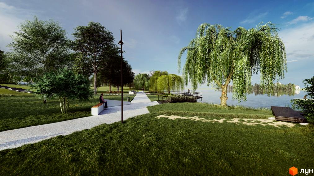 Зображення пішохідної алеї біля води в Котеджному містечку Riverside. Навколо зелені дерева та газон.