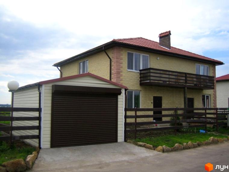 Двоповерховий будинок з гаражем та балконом. На прибудинковій території розташований дерев'яний паркан та газон з камінням.