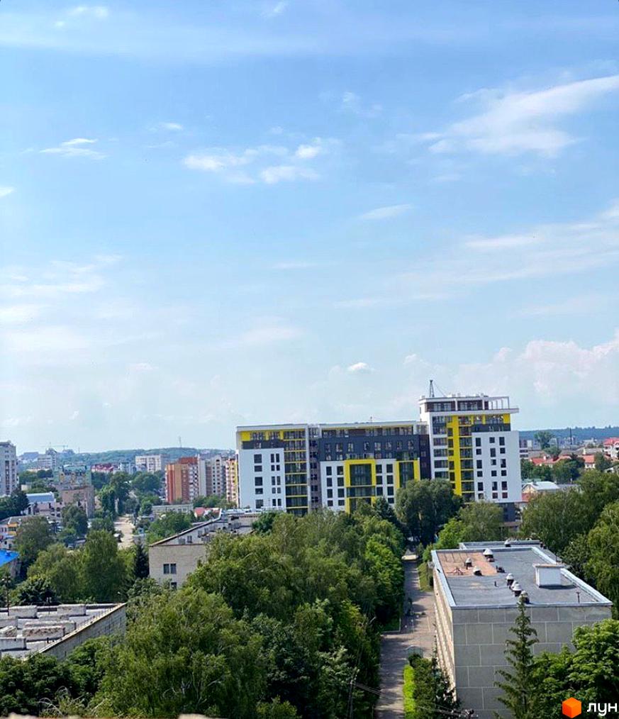 Житловий комплекс Енергія – це сучасна новобудова з яскравим фасадом у жовто-білих кольорах. Навколо комплексу розташовані зелені дерева та міська забудова.