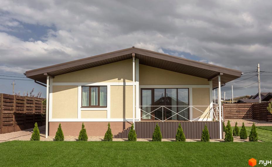 Зображення будинку в Котеджному містечку Графський з газоном та декоративними туями. На задньому плані видно паркан та інші будинки.