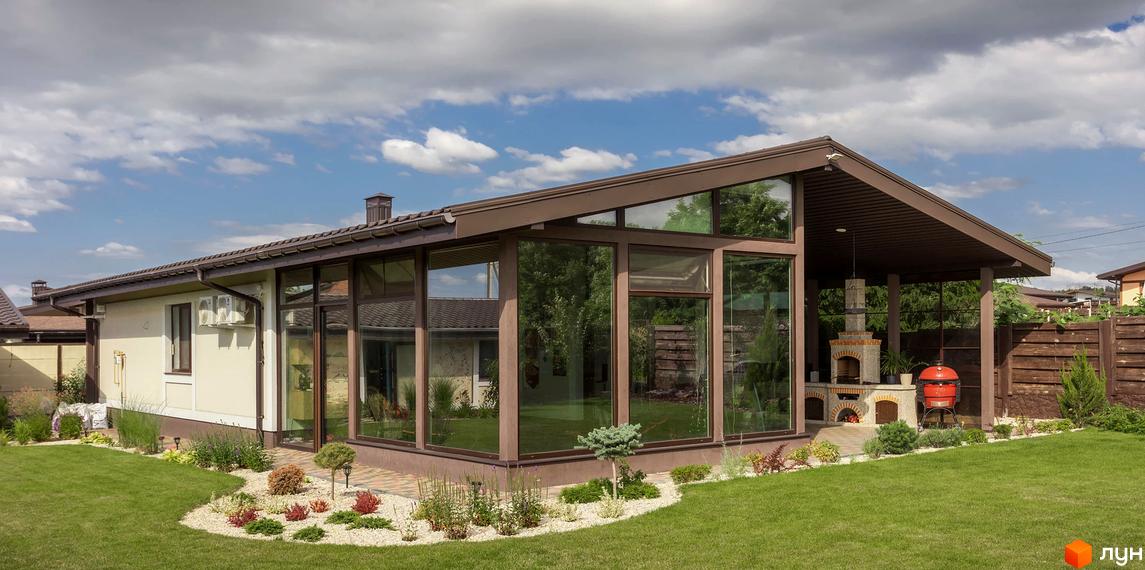 Зовнішній вигляд Котеджного містечка Графський: будинок з великими вікнами та терасою. Навколо зелений газон та ландшафтний дизайн.