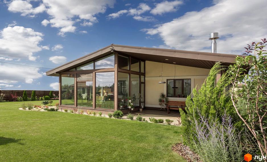 Будинок Котеджного містечка Графський з панорамними вікнами та коричневим дахом. Доглянутий газон та ландшафтний дизайн навколо.