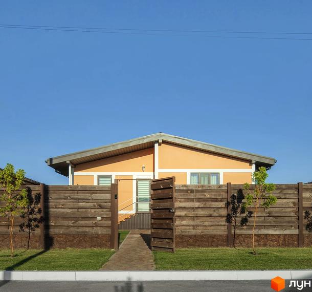 Будинок помаранчевого кольору з сірим дахом у Котеджному містечку Графський. Перед будинком дерев'яний паркан, зелений газон та доріжка.