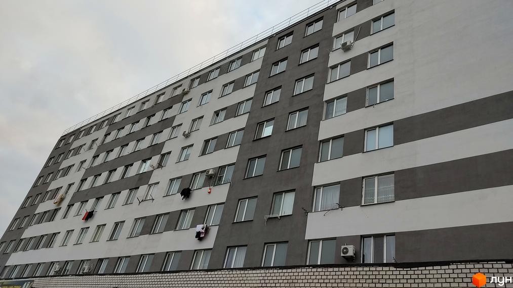 Зовнішній вигляд новобудови Будинок на Боровського з сірими та білими смугами на фасаді. На фасаді багато вікон та кондиціонерів.