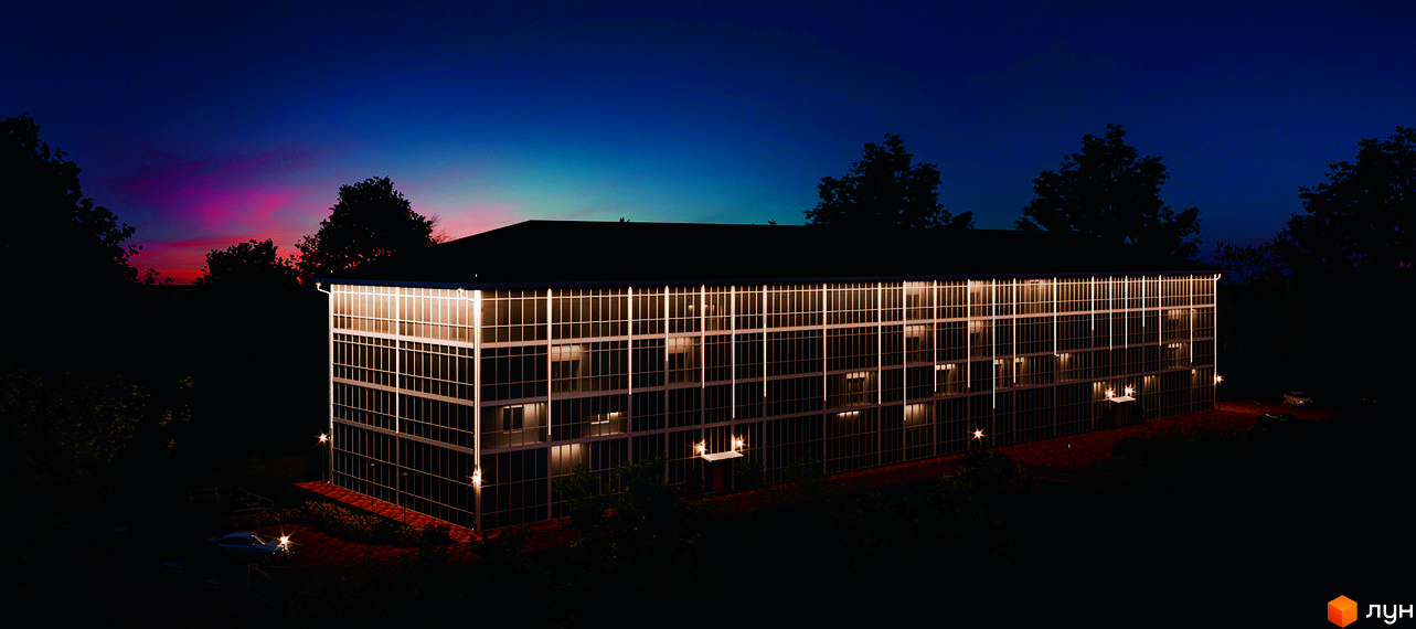 Житловий комплекс Сузір'я 2020 у вечірній час з підсвіченими вікнами та прибудинковою територією з автомобілями.