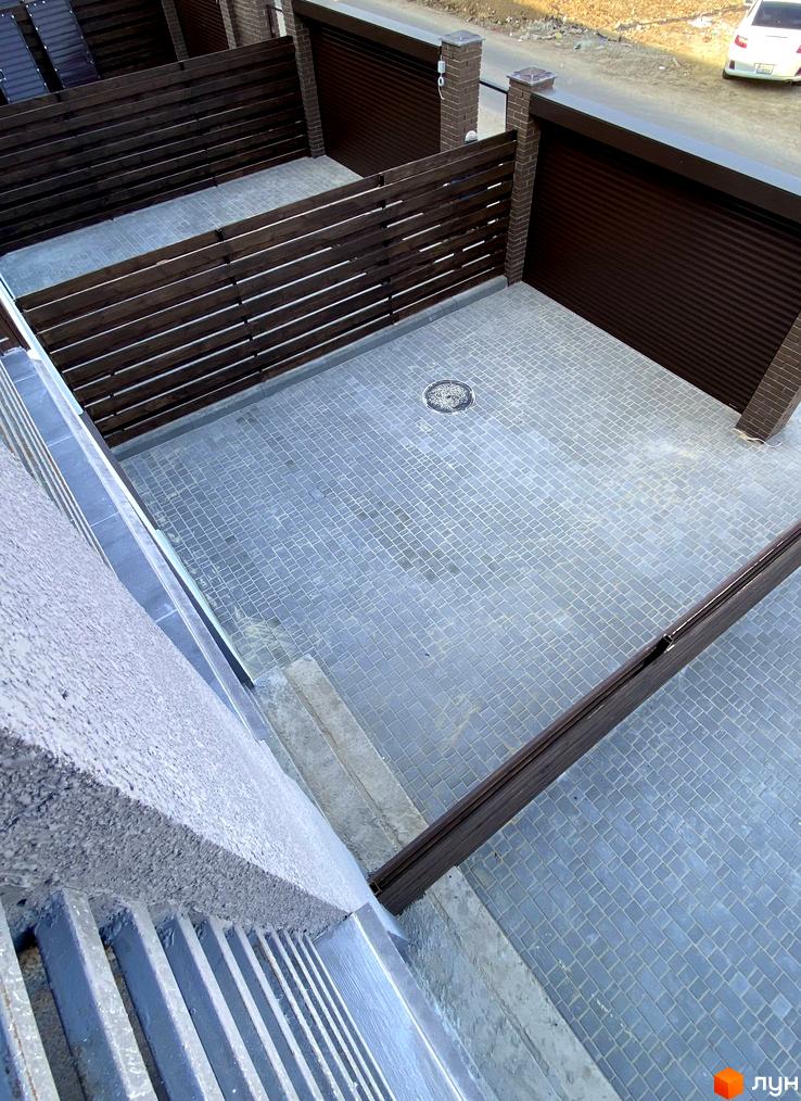 Зовнішній вигляд таунхаусів «Гармонія-3» з брукованою прибудинковою територією та дерев'яним парканом. Огляд території житлового комплексу.