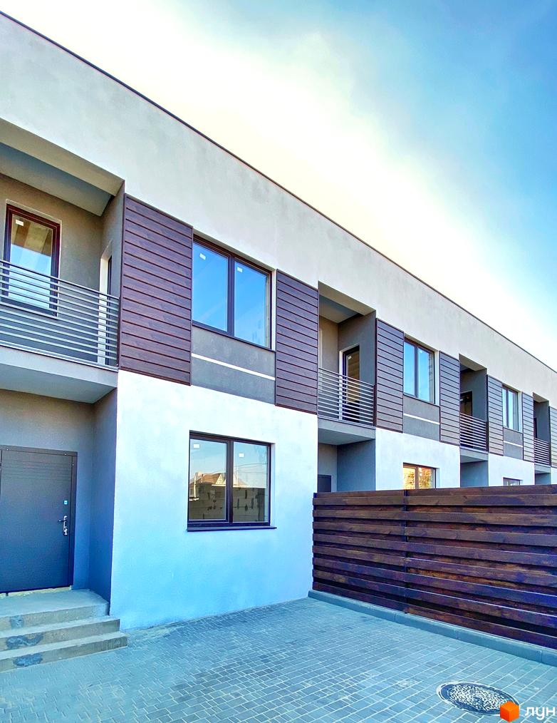 Фасад таунхаусів «Гармонія-3» з великими вікнами та балконами. На подвір'ї бруківка та дерев'яний паркан.