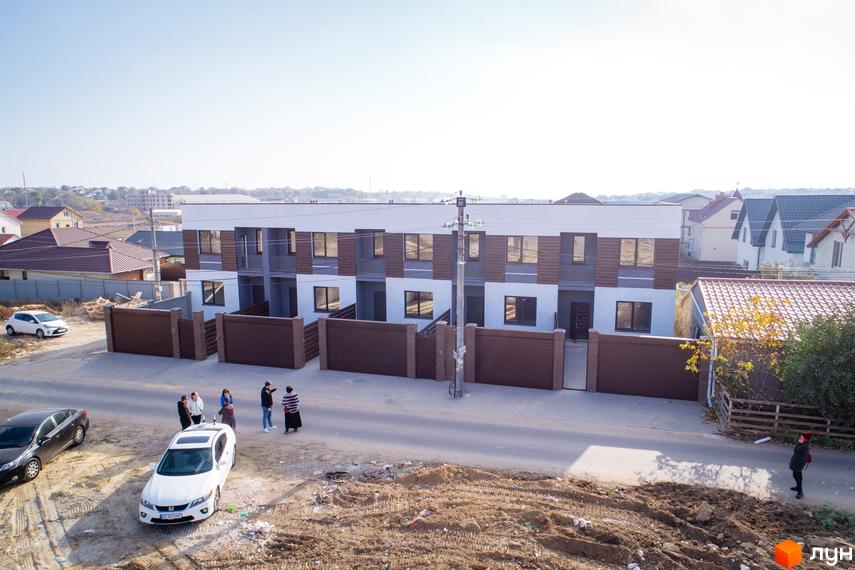 Зображення житлового комплексу таунхаусів «Гармонія-3». Двоповерхові будинки з коричневими секціями на фасаді та огородженою територією.