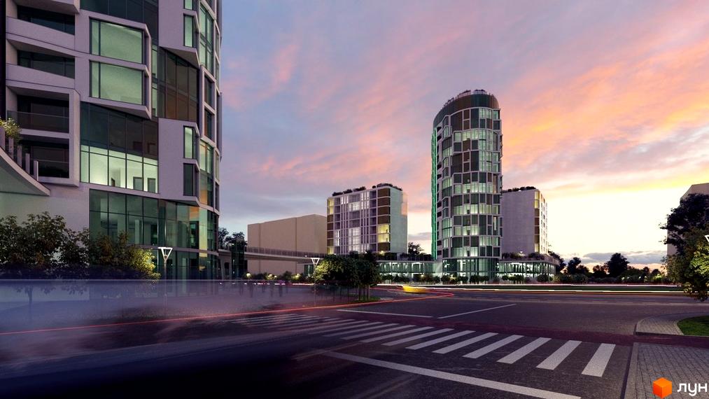 Житловий комплекс Смарагдові вежі з незвичною архітектурою та панорамними вікнами на тлі вечірнього неба. Зелені насадження та освітлені вулиці навколо новобудови.