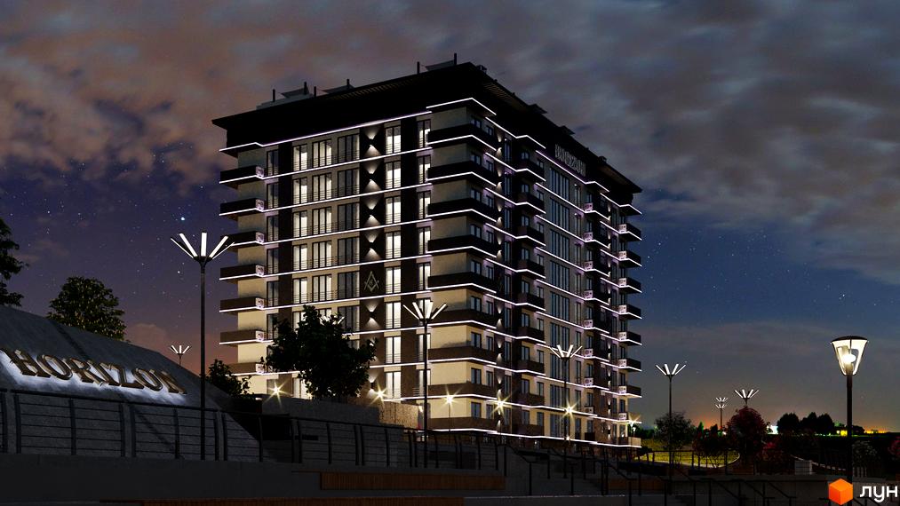 Житловий комплекс Горизонт вночі з підсвіченим фасадом та балконами. На передньому плані видно напис Горизонт та вуличні ліхтарі.