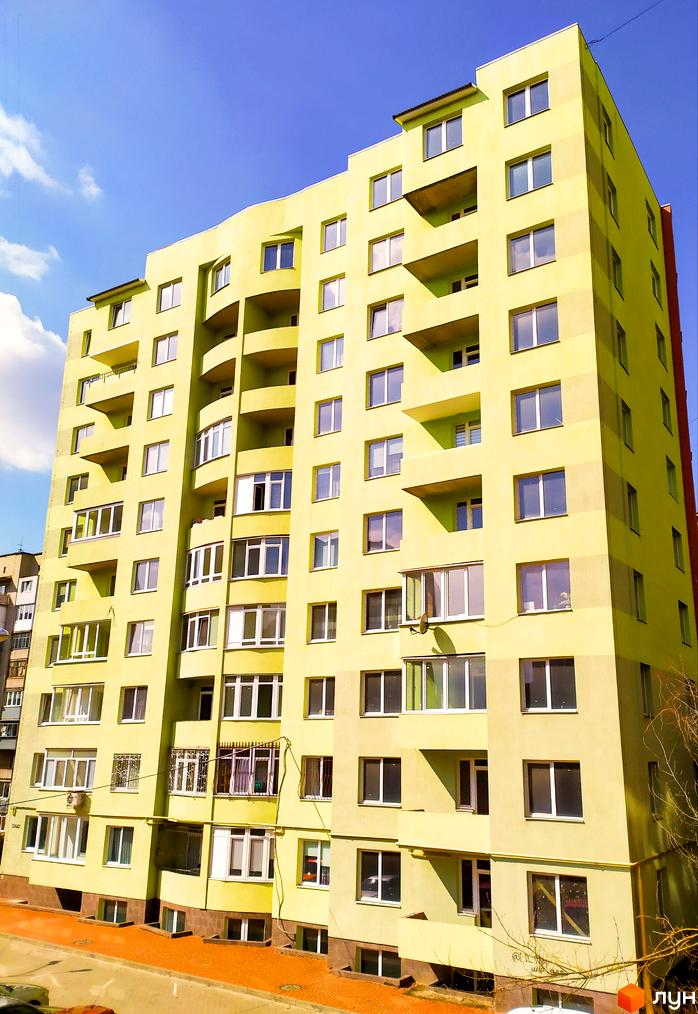 Багатоповерхова новобудова за адресою вул. Яцкова, 20б, світло-жовтого кольору з численними вікнами та балконами. Перед будинком брукована територія.