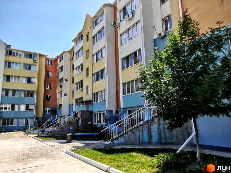 Житловий комплекс Озерки. Зовнішній вигляд багатоповерхових будинків з яскравим фасадом та прибудинкова територія з зеленими насадженнями та лавочками.