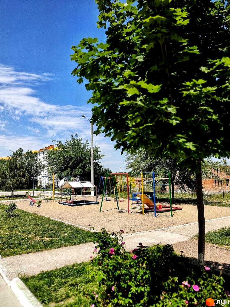 Дитячий майданчик біля багатоповерхового будинку ЖК Озерки. На території комплексу є зелені насадження та пісочниця.