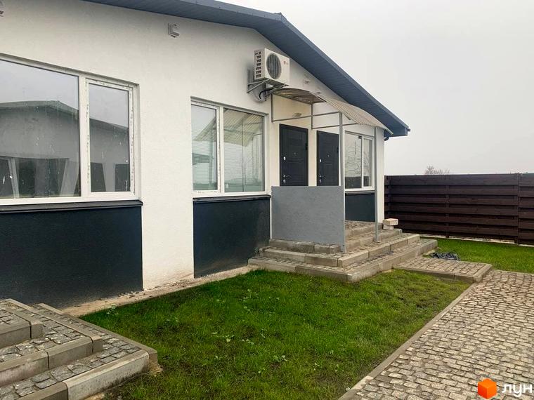 Білий таунхаус „Белгород“ з темною основою та білими вікнами. Перед будинком зелений газон та вимощена доріжка.