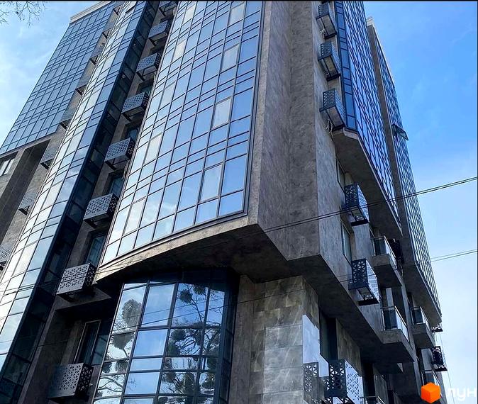 Сучасний житловий комплекс Зелений замок з панорамним склінням та балконами з ажурними решітками. Зовнішній вигляд будівлі вражає своєю геометричністю та об'ємністю.