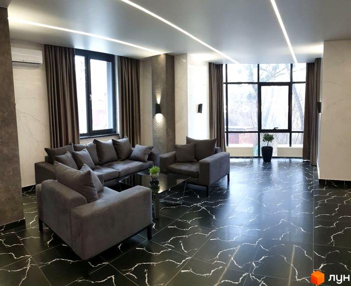 Просторий зал житлового комплексу Зелений замок з великими вікнами та диванами. Сучасний дизайн інтер'єру з мармуровою підлогою та вбудованим освітленням.