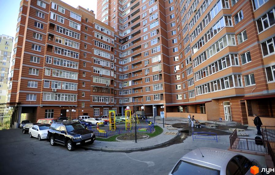 Житловий комплекс Ревуцького, 9 з сучасною фасадною обробкою та прибудинковою територією з дитячим майданчиком і паркувальними місцями.