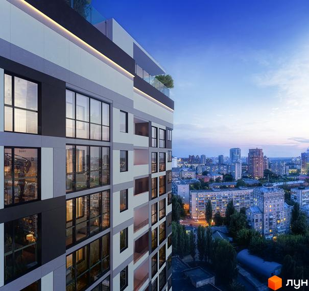 Фасад житлового комплексу High Hills з великими вікнами та балконами на тлі вечірнього міста. Навколо комплексу видно міську забудову та дерева.
