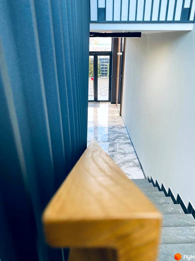 Інтер'єр житлового комплексу CENTRAL HOUSE з мармуровою підлогою та дерев'яними поручнями сходів. Сучасний дизайн внутрішнього простору новобудови.