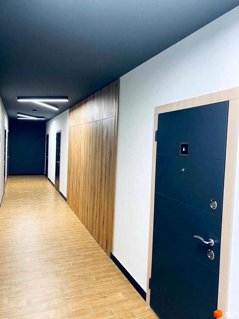 Коридор Житлового комплексу CENTRAL HOUSE з дерев'яною підлогою, темною стелею, стіною з дерев'яними панелями та вхідними дверима.