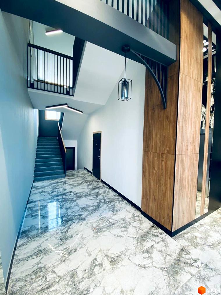 Сучасний інтер'єр сходової клітини в ЖК CENTRAL HOUSE з мармуровою підлогою та дерев'яними елементами.