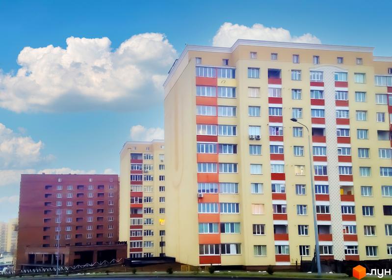 Зображення фасаду багатоповерхового будинку по вулиці Січових Стрільців, 5. Житловий комплекс з великими вікнами на фоні блакитного неба.