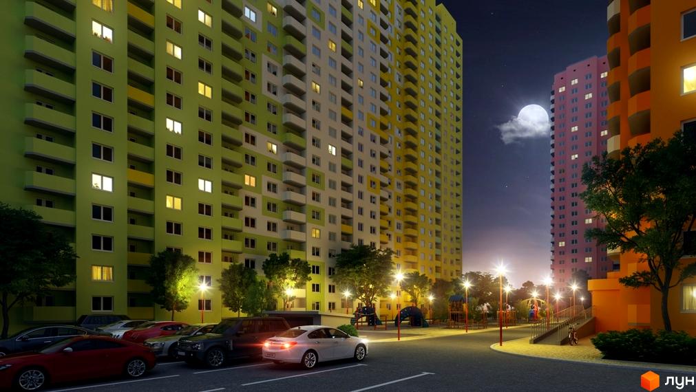 Житловий комплекс Амурський у вечірній час. Багатоповерхові будинки з яскравим фасадом та освітленими вікнами. Поруч дитячий майданчик та парковка з автомобілями.