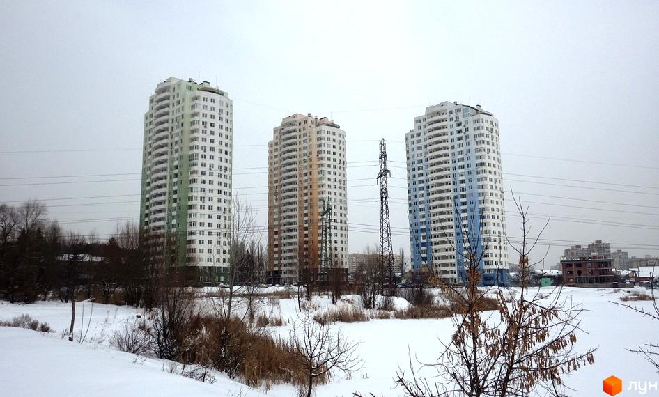 Житловий комплекс Озерний на Обухівській, 135а. Три висотні будинки з балконами на тлі зимового пейзажу та ліній електропередач.