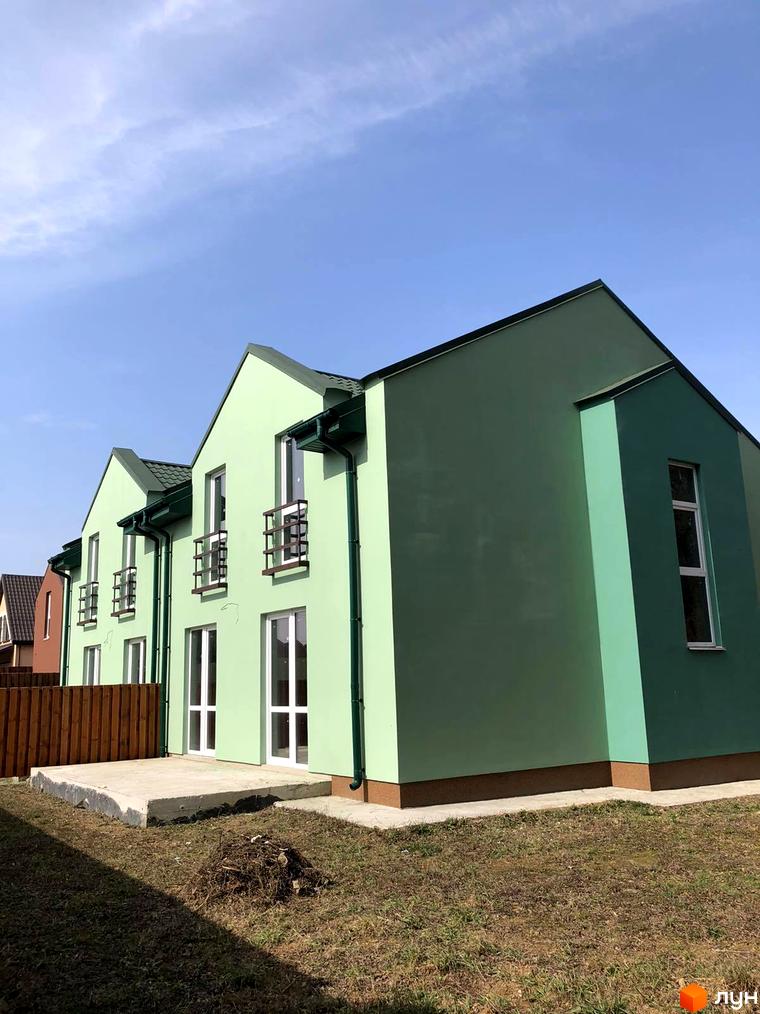 Котеджне містечко Sunny Village: світло-зелені котеджі з темними дахами та білими вікнами. Прибудинкова територія з травою та дерев'яним парканом.