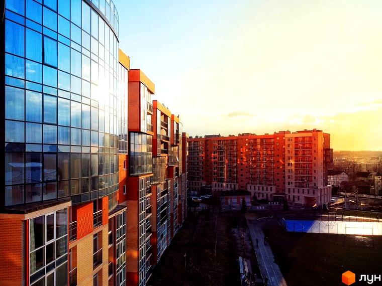 Житловий комплекс Водограй: багатоповерхова будівля з панорамними вікнами та цегляними елементами. Поруч видно спортивні майданчики та доріжки.