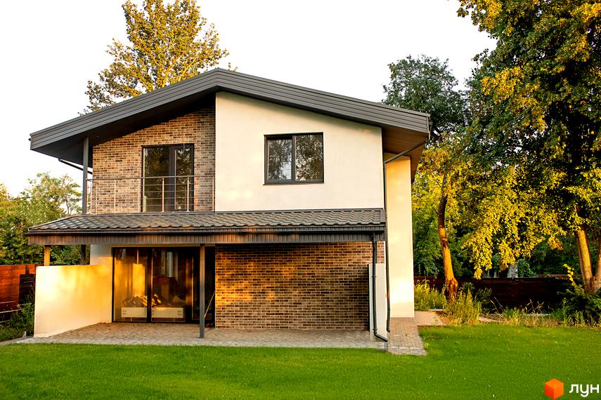 Котеджне містечко КМ Чайковка Hills. Зовнішній вигляд будинку з цегляним фасадом та білою штукатуркою, прибудинкова територія з доглянутим газоном та деревами.