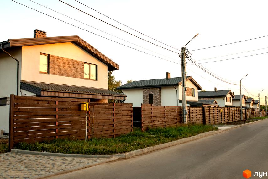 Котеджне містечко Чайковка Hills: сучасні котеджі з цегляними вставками та дерев'яними парканами. Озеленена прибудинкова територія з доглянутими газонами.