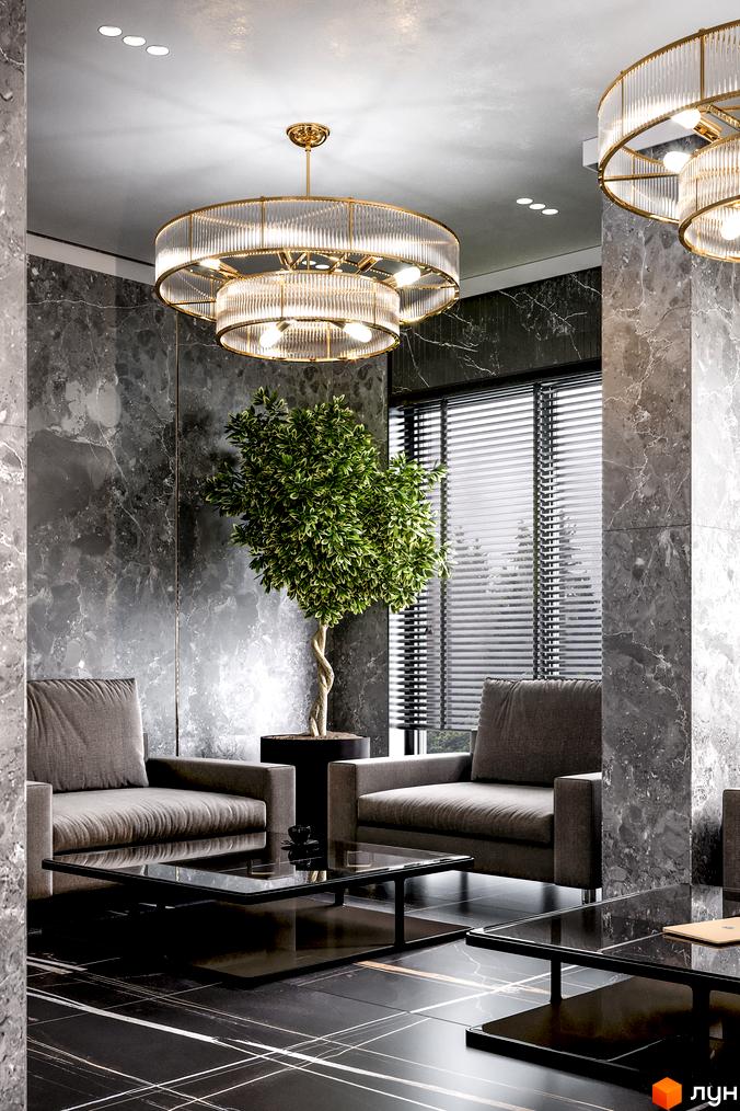 Інтер'єр вітальні в житловому комплексі Rusaniv Residence з сірими диванами, мармуровими стінами та підлогою, а також двоярусною люстрою.