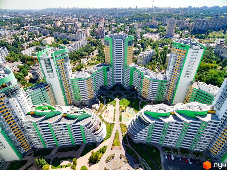 Житловий комплекс Паркове місто: висотні будівлі біло-зеленого кольору з жовтими елементами та вигнутими формами. Внутрішній двір з зеленими зонами та дитячими майданчиками.
