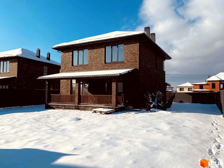 Котеджне містечко КМ Весняний: цегляні двоповерхові будинки з коричневої цегли під снігом, з ґанком та дерев'яними перилами. Навколо засніжена ділянка з доріжкою зі слідів.