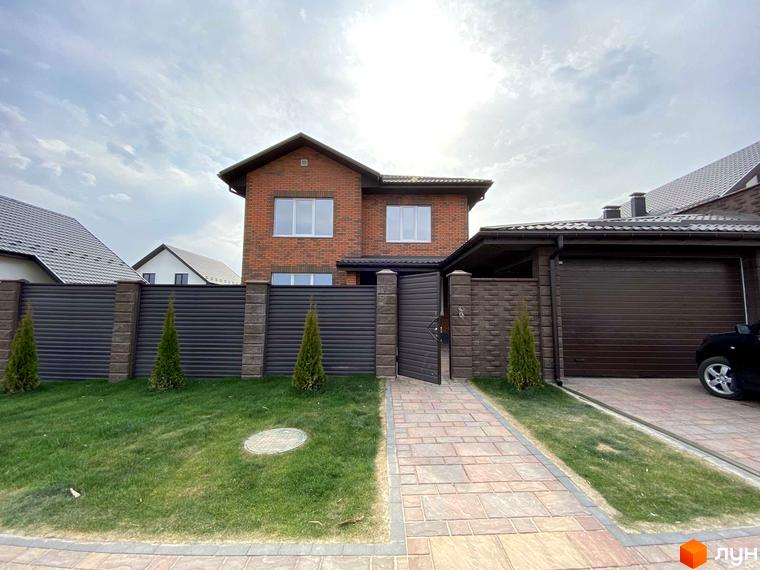 Котеджне містечко КМ Весняний: цегляний двоповерховий будинок з гаражем та доглянутою прибудинковою територією з газоном та парканом.