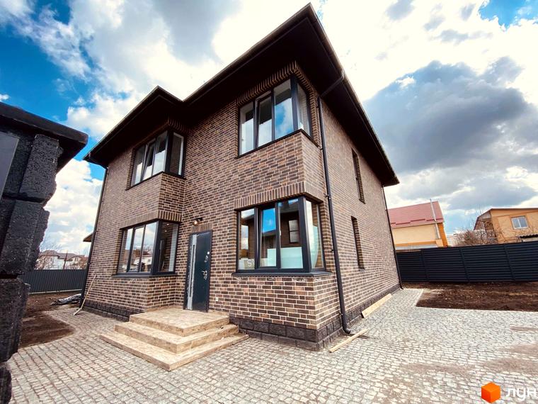 Котеджне містечко КМ Весняний: двоповерховий будинок з цегляним фасадом та бруківкою на прибудинковій території.