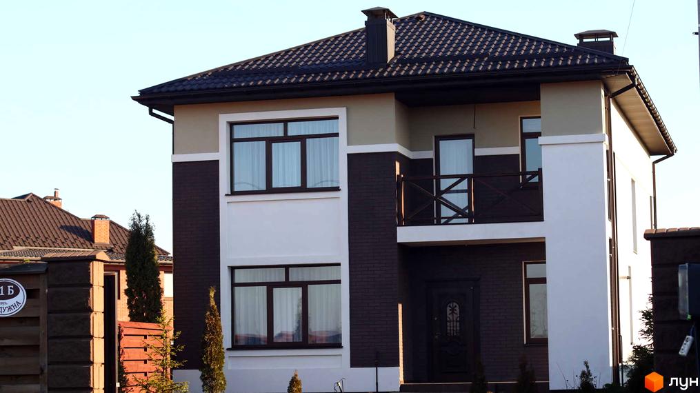 Котеджне містечко Весняний: двоповерховий будинок з темним дахом та фасадом з контрастних кольорів. Прибудинкова територія з парканом та деревами.