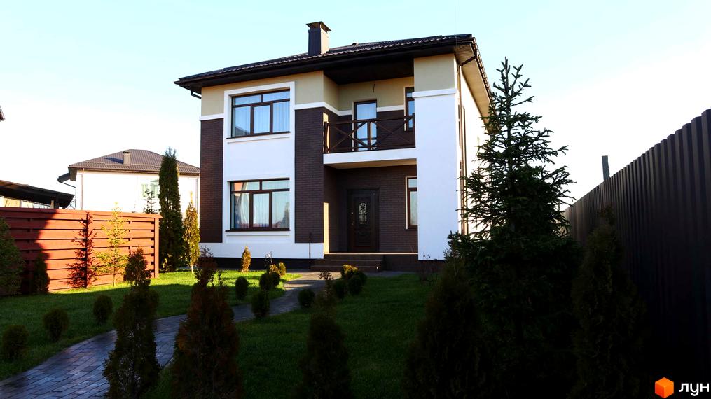 Котеджне містечко КМ Весняний: двоповерховий будинок з білою та коричневою обробкою, балконом та доглянутим газоном з доріжкою.