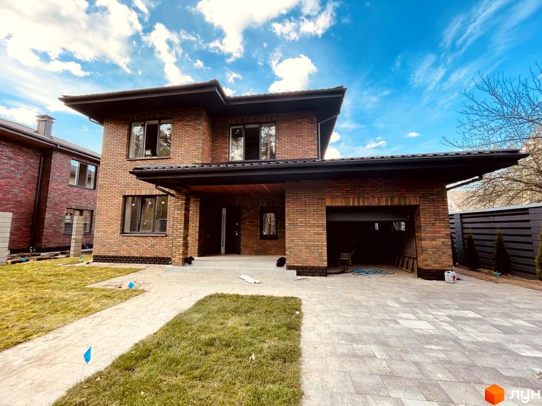 Котеджне містечко КМ Лісова Білогородка: двоповерховий цегляний будинок з гаражем та впорядкованою прибудинковою територією.