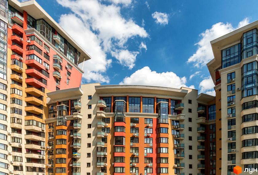 Житловий комплекс Сонячна брама: багатоповерхові будинки з фасадами бежевого, помаранчевого та червоного кольорів, балконами та великими вікнами.