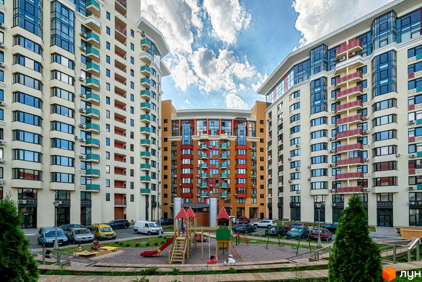 Житловий комплекс Сонячна брама: світлі багатоповерхові будинки з кольоровими балконами. У дворі облаштований дитячий майданчик та парковка.